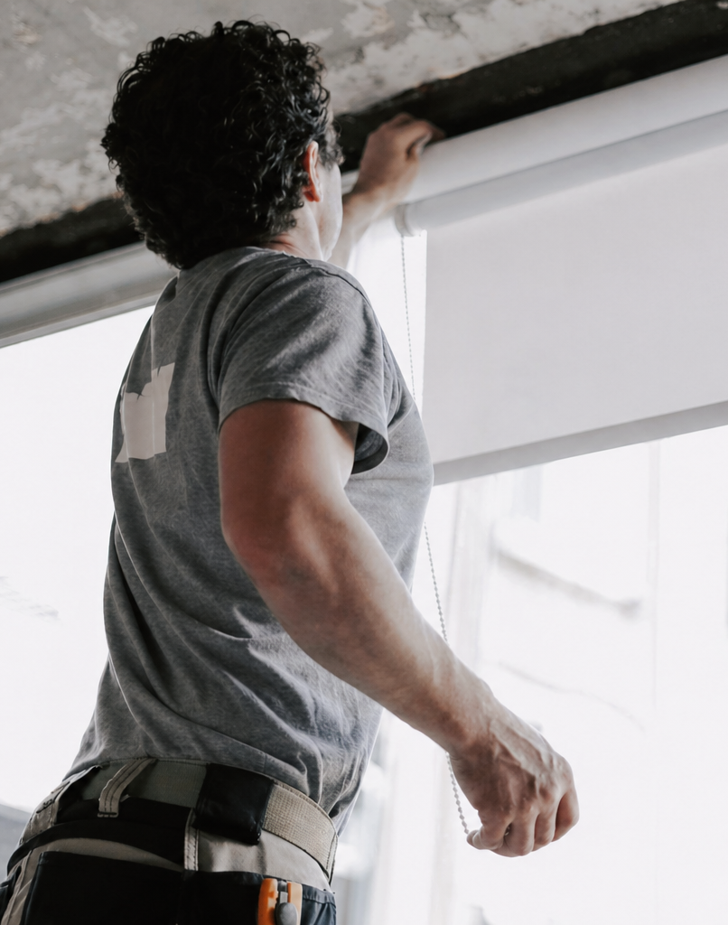 Installer fitting a roller blind above a window